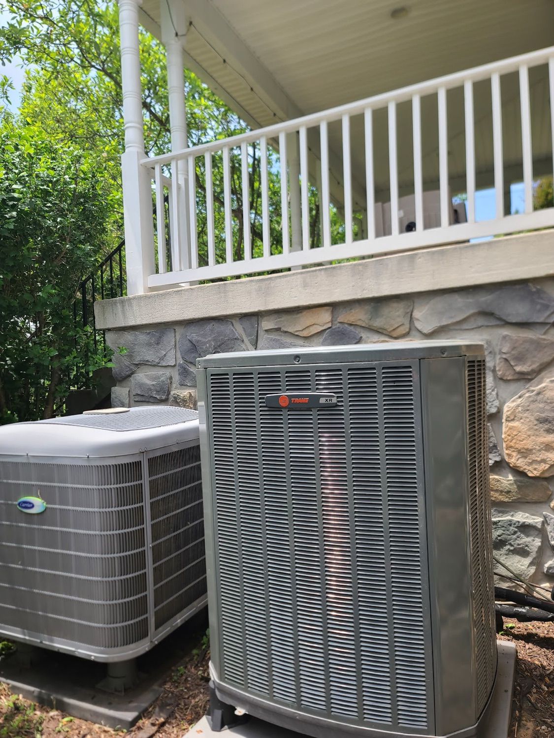 High-efficiency Carrier condenser installed beside a stone-front home